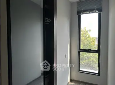 Compact bedroom with large window and built-in closet, offering natural light and modern design.