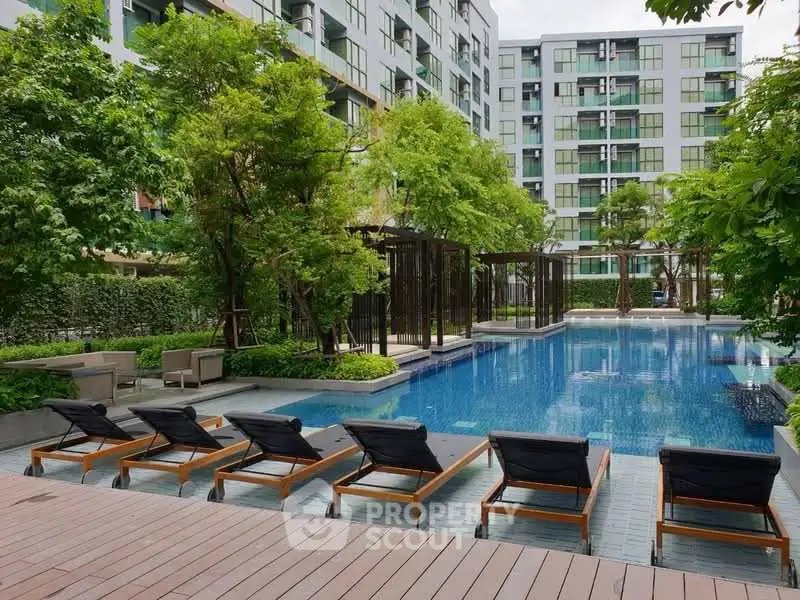Luxurious condominium pool area with sun loungers and lush greenery, perfect for relaxation and leisure.