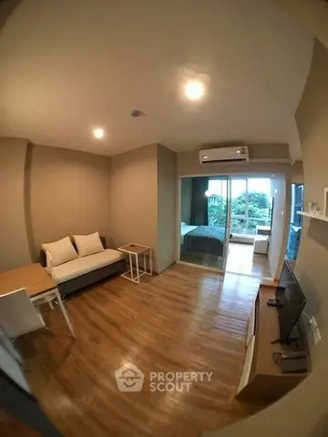 Cozy living room with wooden flooring and modern furnishings, featuring a view of the balcony.
