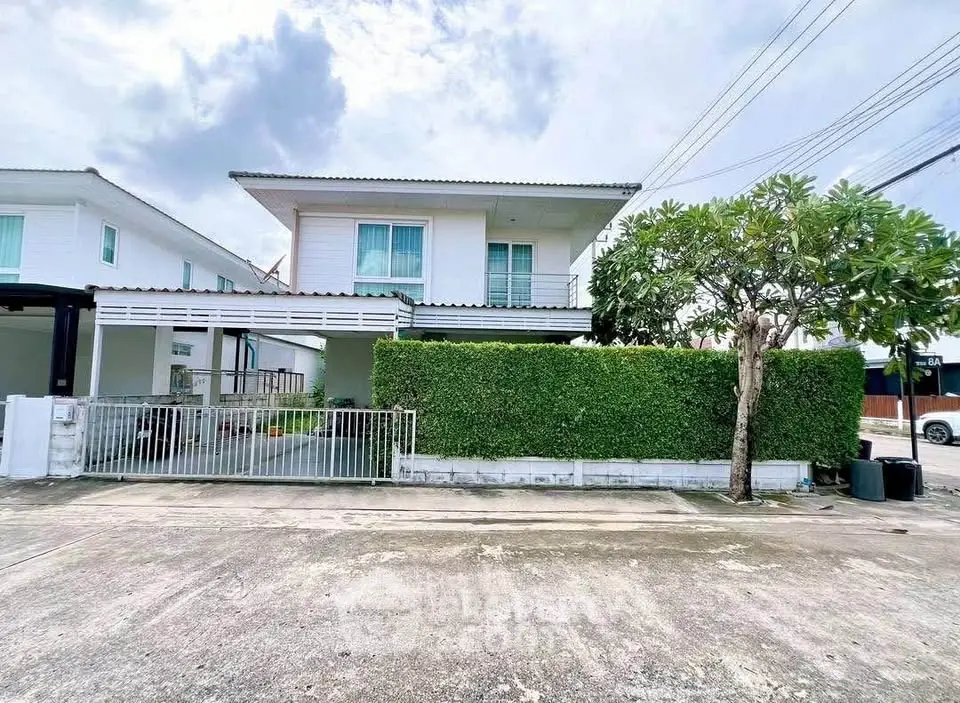 Charming two-story house with lush green hedge and spacious driveway in a serene neighborhood.