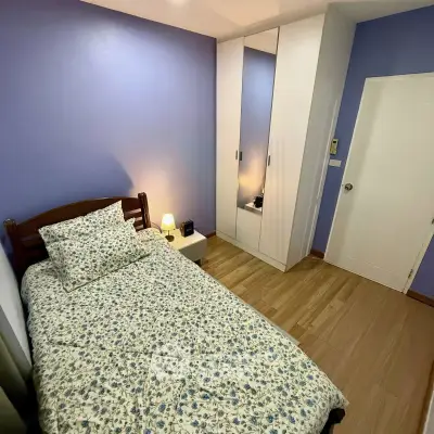 Cozy bedroom with floral bedding and modern wardrobe in a stylish apartment.