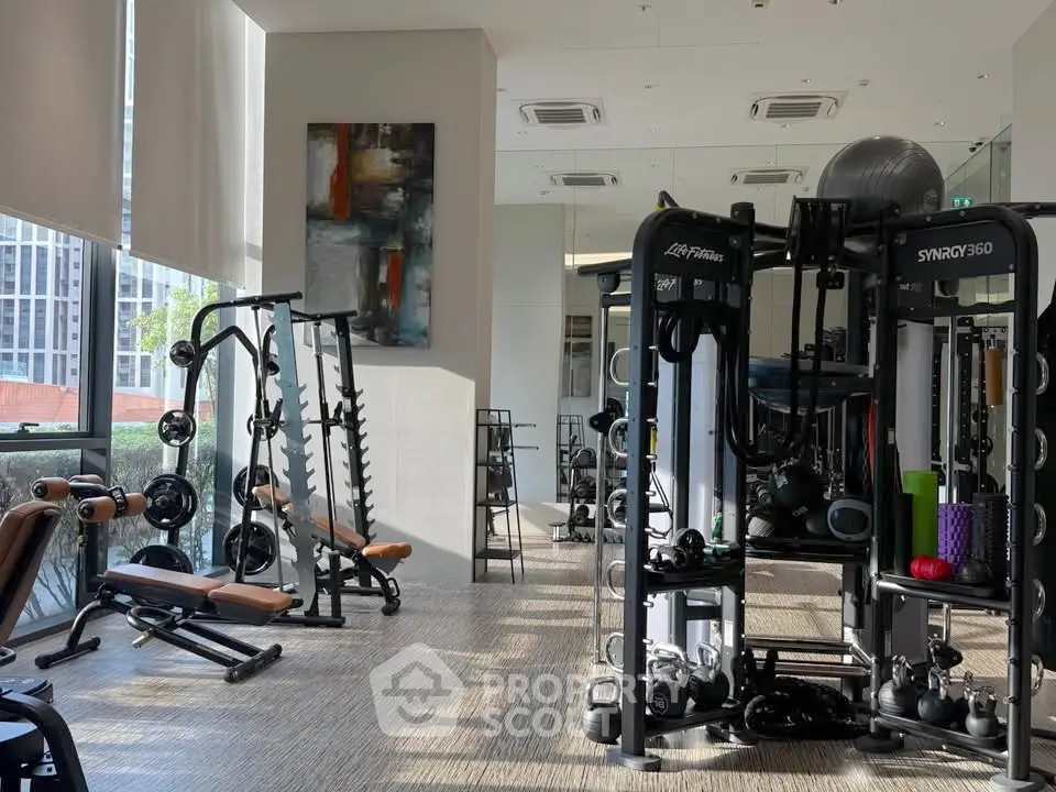 Modern gym with state-of-the-art fitness equipment and large windows offering natural light.