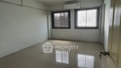 Spacious empty room with large windows and air conditioning unit, perfect for customization.