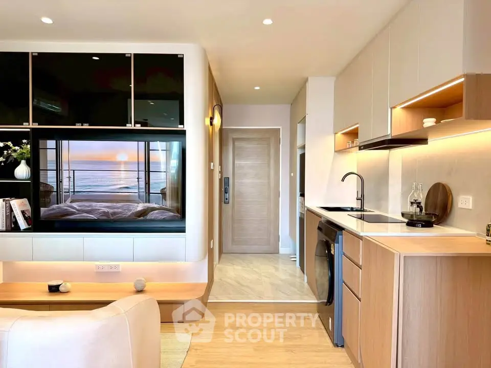 Modern open-layout living room with sleek kitchen and cozy decor, featuring a stylish washing machine.