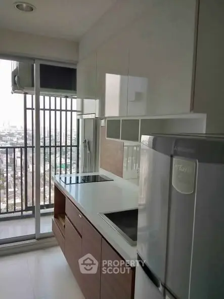 Modern kitchen with sleek appliances and balcony view in urban apartment