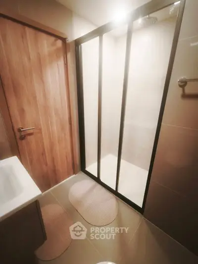 Modern bathroom with sleek shower enclosure and wooden door