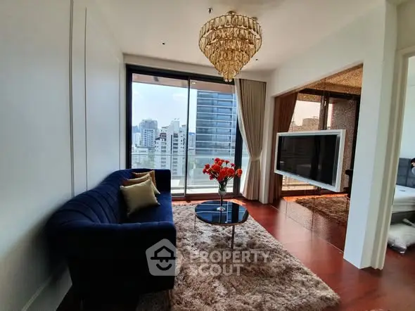 Luxurious living room with chandelier and city view, featuring modern decor and plush furnishings.