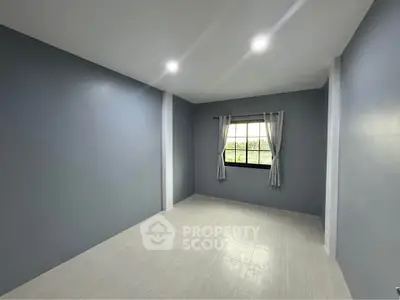 Spacious empty room with large window and modern gray walls, perfect for customization.