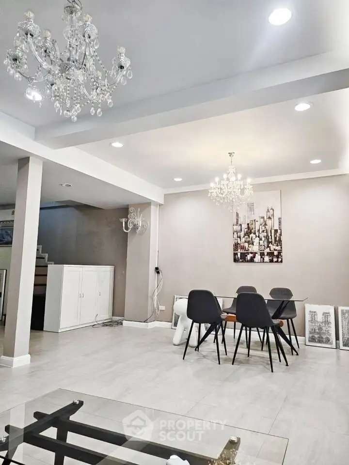 Elegant dining area with modern decor and chandeliers in a spacious open-plan living room.