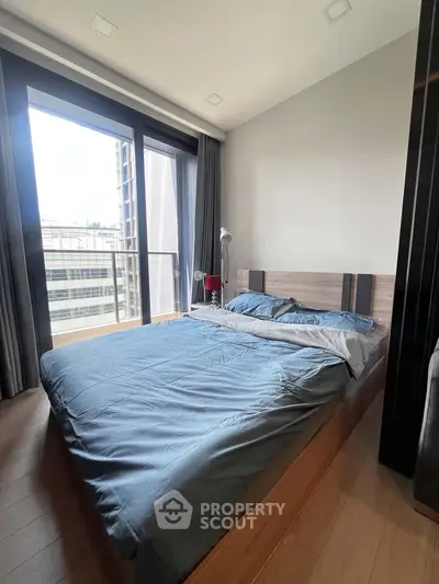 Modern bedroom with large window and city view, featuring a cozy bed and stylish decor.