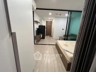 Modern studio apartment with sleek design and glass partition, featuring a cozy bed and minimalist decor.