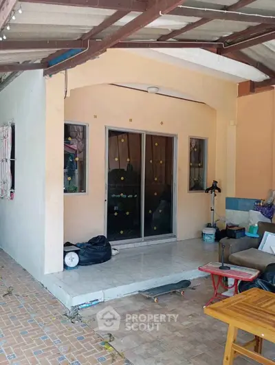 Charming covered patio with sliding glass doors and tiled flooring, perfect for relaxation.