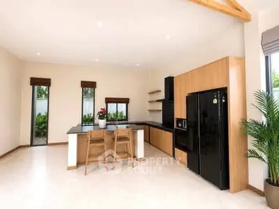Spacious modern kitchen with sleek black appliances and wooden cabinetry, featuring an open layout and natural light.