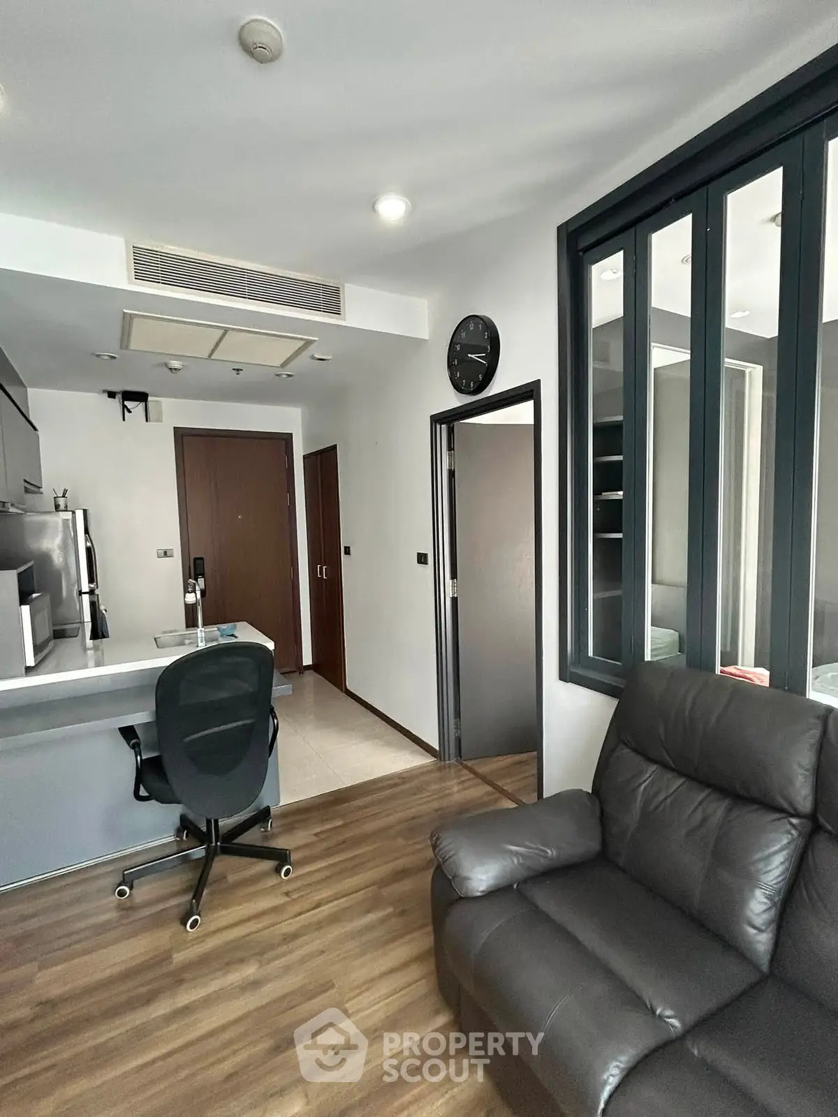 Modern apartment interior with sleek kitchen and cozy living area, featuring stylish furniture and wooden flooring.