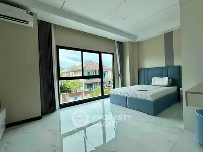 Spacious bedroom with large window offering a serene view, modern furnishings, and ample natural light.