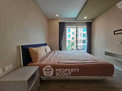 Spacious bedroom with large window and modern furnishings in a stylish apartment.