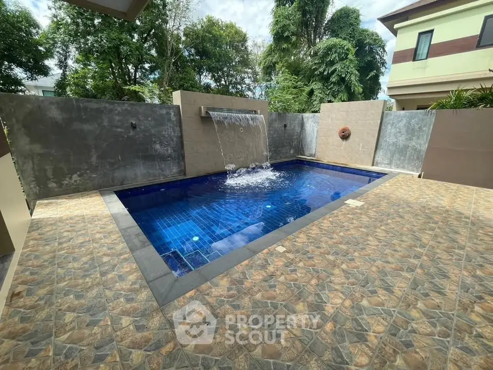 Luxurious private pool with waterfall feature in modern backyard setting.
