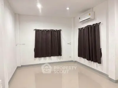 Spacious empty room with air conditioning and large windows, perfect for customization.