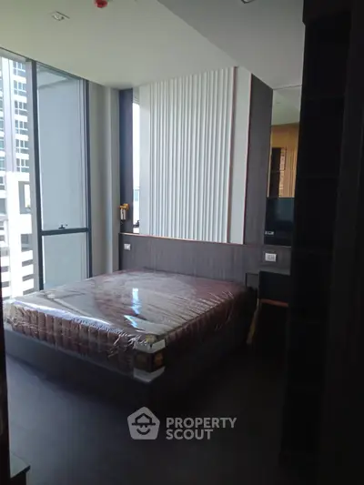 Modern bedroom with large windows and sleek design in high-rise apartment.