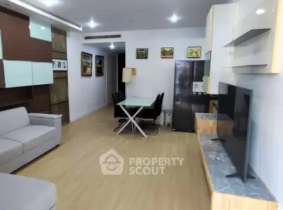 Modern living room with sleek furniture and open layout, featuring a dining area and large TV.