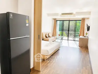 Modern studio apartment with open layout, featuring a cozy living area and large windows for natural light.