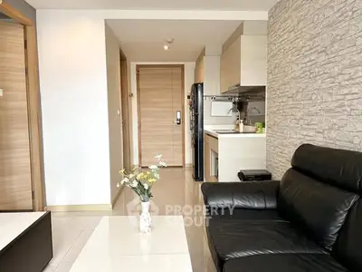 Modern living room with sleek black leather sofa and stylish kitchen area