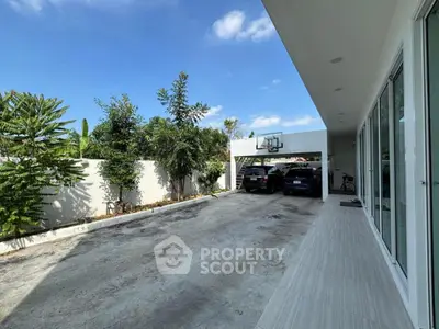 Spacious modern driveway with basketball hoop and lush greenery