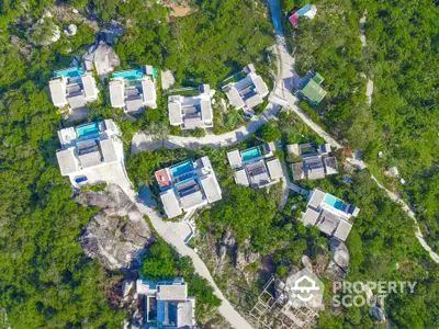 Aerial view of luxury villas with private pools nestled in lush greenery.