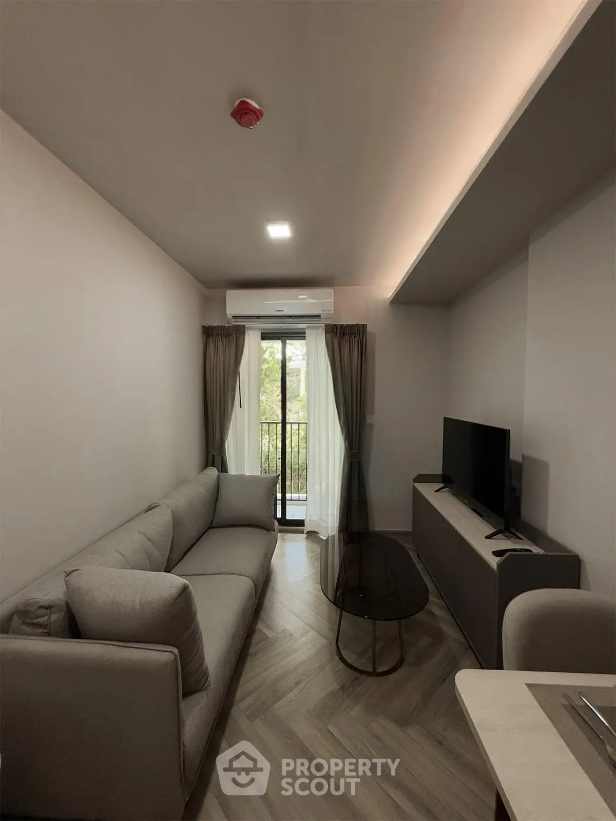 Modern living room with cozy sofa, TV, and balcony view in stylish apartment.