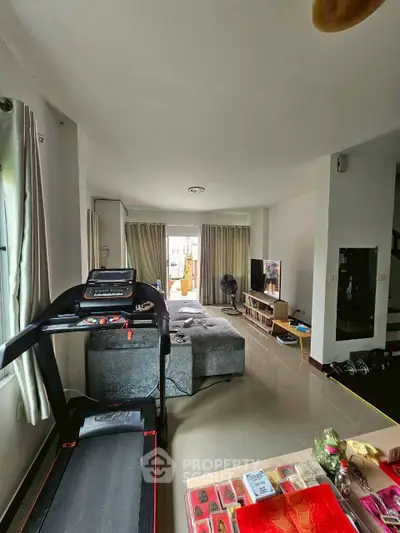 Spacious living room with modern decor and treadmill, perfect for relaxation and fitness.
