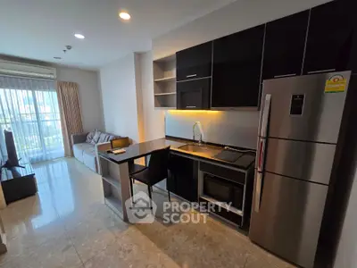 Modern open-layout kitchen with sleek black cabinets and stainless steel appliances in a stylish apartment.