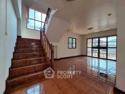 Spacious living room with wooden staircase and large windows for natural light.