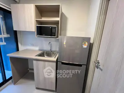 Modern compact kitchen with microwave and fridge in sleek apartment