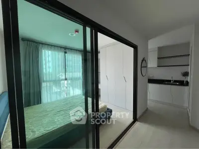 Modern apartment with glass partitioned bedroom and sleek kitchen.