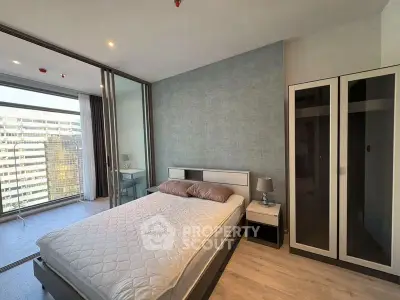 Modern bedroom with floor-to-ceiling windows and city view, featuring sleek furniture and ample natural light.