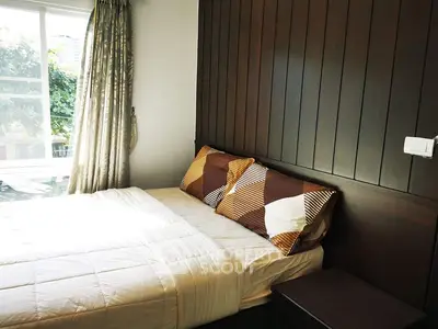 Cozy bedroom with modern decor and large window offering natural light.
