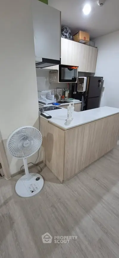 Modern kitchen with sleek cabinetry and appliances, featuring a compact open layout and stylish flooring.