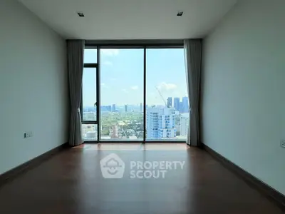 Spacious empty room with floor-to-ceiling windows offering stunning cityscape views.