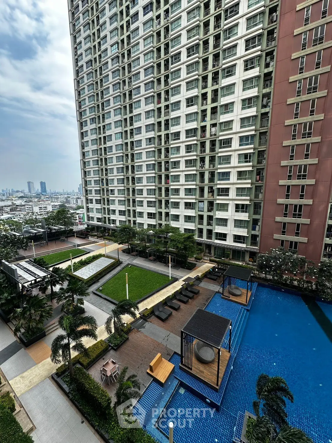 Luxurious high-rise apartment with pool and garden view in urban setting.