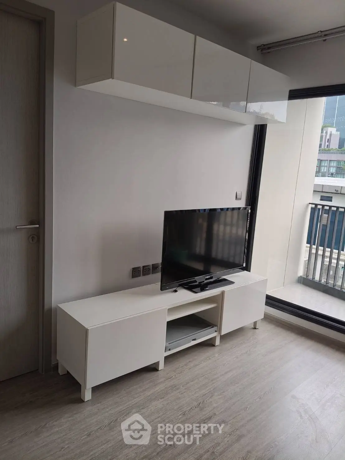 Modern living room with sleek TV stand and balcony view in a stylish apartment.