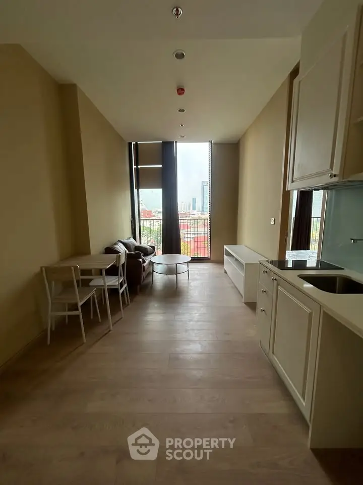 Modern apartment with open layout, featuring a cozy living area and kitchen, offering a city view through large windows.