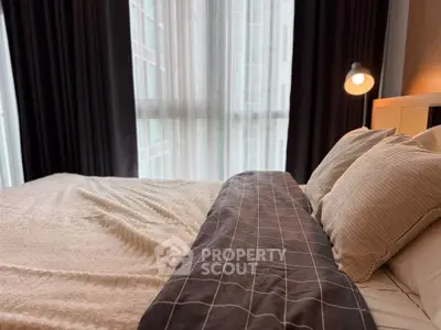 Cozy bedroom with large window and elegant bedding in modern apartment.