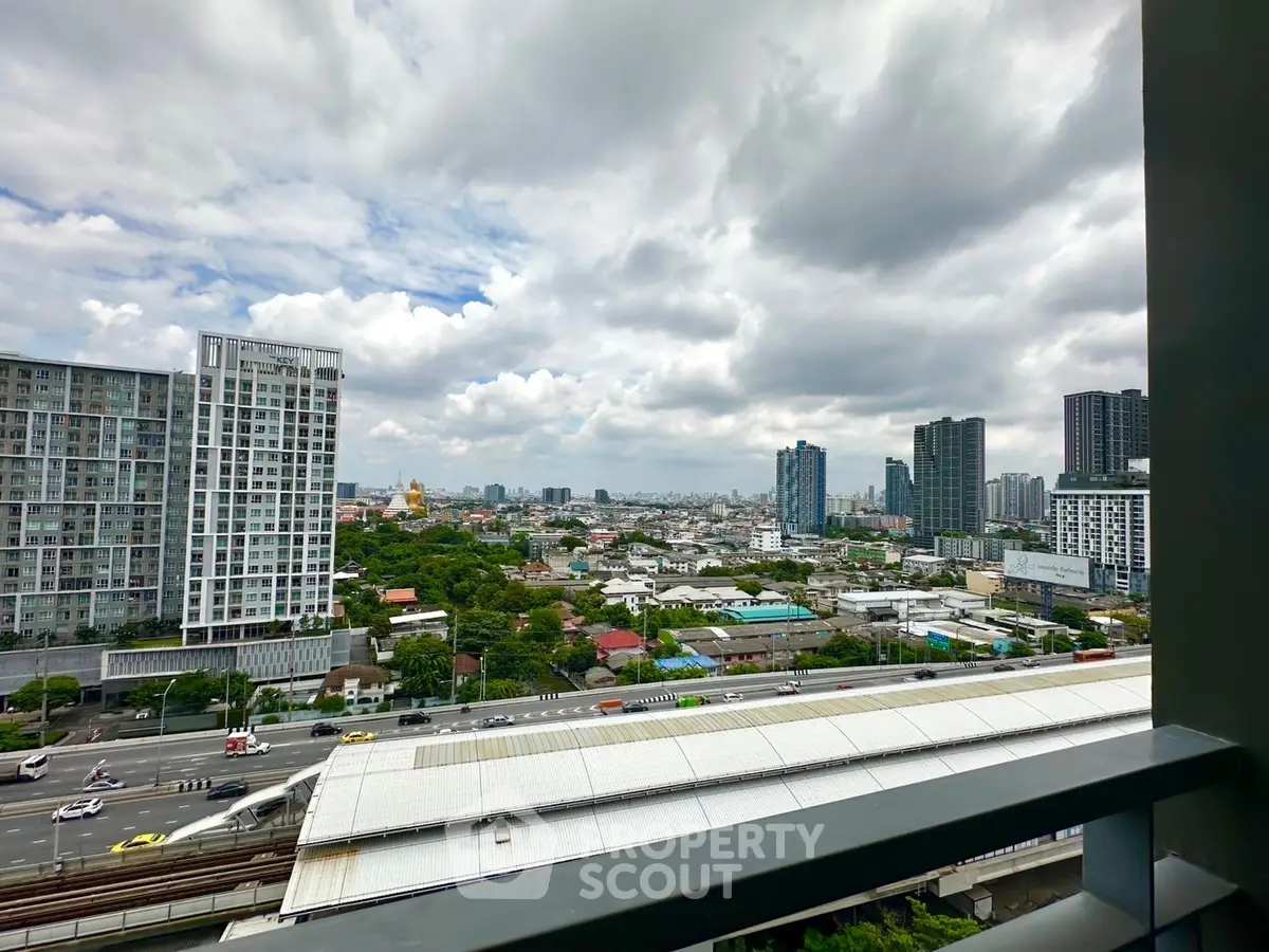 Stunning cityscape view from a high-rise balcony overlooking urban skyline and lush greenery.