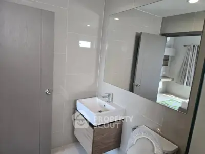 Modern bathroom with sleek fixtures and large mirror in contemporary home.