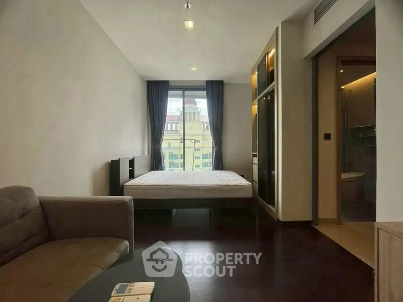 Modern bedroom with large window and cozy seating area.