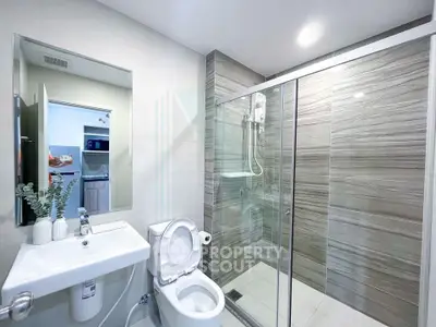 Modern bathroom with glass shower and sleek fixtures in contemporary apartment.
