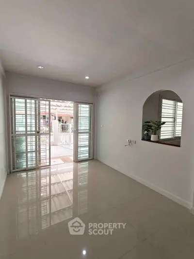 Spacious living room with large windows and glossy tiled floor, perfect for natural light lovers.