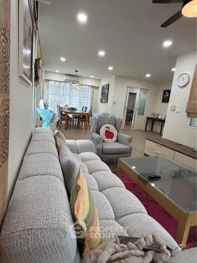 Spacious living room with modern decor and dining area, featuring cozy seating and elegant lighting.
