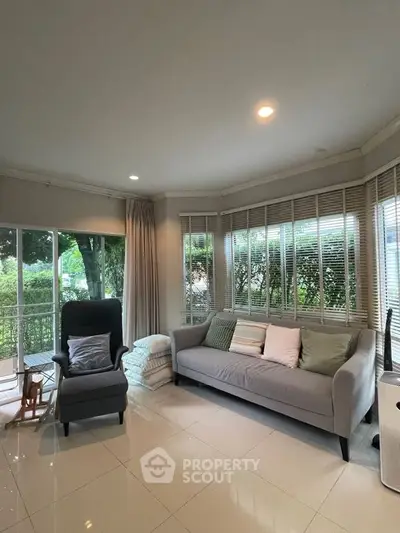 Spacious living room with large windows and modern furniture, perfect for relaxation.