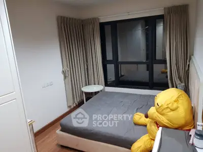 Cozy bedroom with large window and plush toy, perfect for relaxation.
